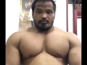 Young Thai hunk showing off his muscles and posing like a bodybuilder.
